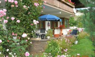 A beautiful house with a blooming garden.  
Colorful flowers surround a terrace with a blue umbrella.