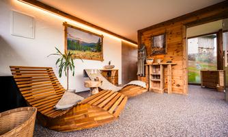 A cozy relaxation room with wooden furniture and a nice atmosphere. A plant and pictures on the walls complete the relaxing ambiance.