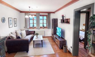 A cozy living room with a comfortable sofa and a television.  
Large windows provide plenty of daylight and an inviting atmosphere.