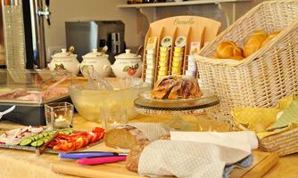 A lovely breakfast buffet with a selection of fresh rolls, cold cuts, and fruit. On the table, there are also jams and various types of bread arranged.