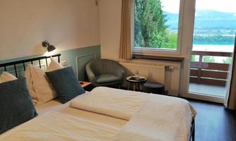 A cozy room with two beds and a view of nature. There is a small table and chairs on the balcony.