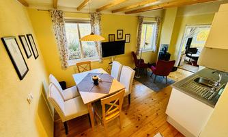 A cozy interior with a dining area and a small kitchen. Large windows provide plenty of natural light and an inviting atmosphere.