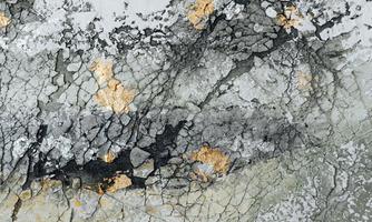 An abstract surface with cracks and varying shades of gray. Golden accents give the image a special touch.