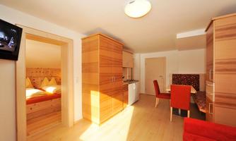 A bright apartment with modern wood design. It features a kitchen, a dining area, and a bedroom.