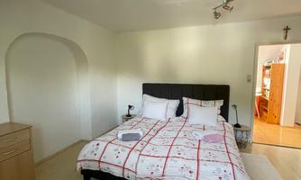 A cozy bedroom with a large bed. A dresser is visible on the side.