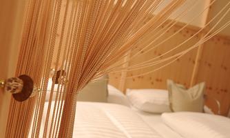 A modern bedroom with two beds and elegant cushions. Wooden threads serve as a decorative element in the room.
