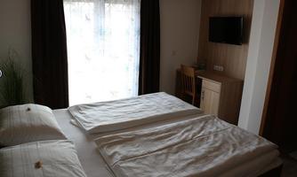 A cozy room with a double bed and two blankets. There is a television and a small table in the corner.