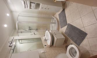A modern bathroom with a shower, a sink, and a toilet. The walls are light and there are clean towels.