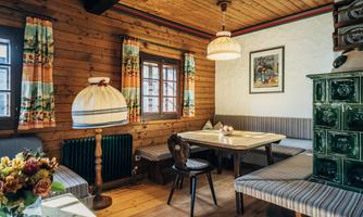 A cozy room with wooden paneling and an inviting seating area. The table is decorated, and a lamp provides warm light.