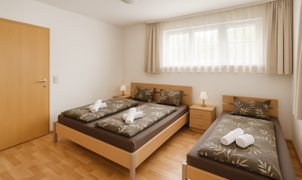A modern bedroom with two single beds and light wooden flooring. Next to the beds are nightstands with lamps, and the windows provide daylight.