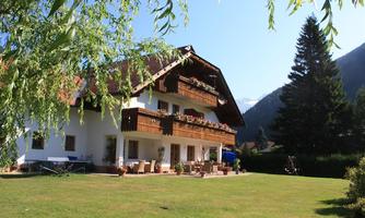 A beautiful, spacious house with a large garden and balconies. Surrounded by trees and mountains, the scene radiates tranquility and a connection to nature.