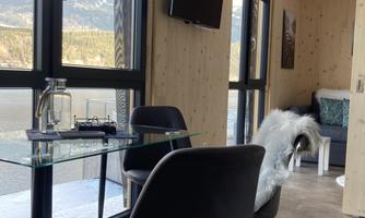 A modern room with a glass workspace and black chairs. Large windows offer a view of the mountains.