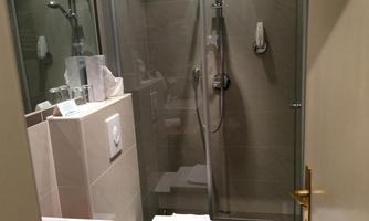 A modern bathroom with a glass shower. The walls are in neutral colors and there is a sink with wooden details.