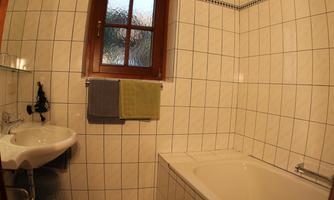 A bathroom with colorful towels, a sink, and a bathtub. A window provides daylight and a friendly atmosphere.