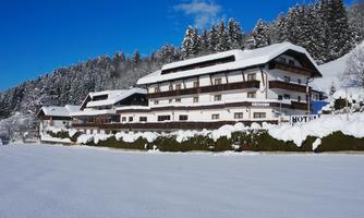 A picturesque hotel in a snowy landscape. The sky is clear and blue, surrounded by snow-covered mountains.