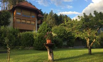 A beautiful house surrounded by green trees and well-maintained grass. The sky is blue with a few clouds.