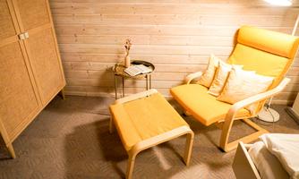 A cozy seating area with an orange armchair and a matching table. In the background, there are wooden shelves that create a warm atmosphere.