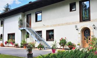 A modern house with a charming facade and stairs. Flowers in pots surround the entrance area.