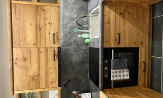 A modern kitchen with wooden cabinets and dark countertops. It is equipped with appliances such as a stove and a sink.