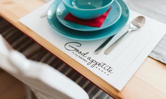 A laid table with blue bowls and a red napkin on a placemat. On it is the inscription "Good appetite".
