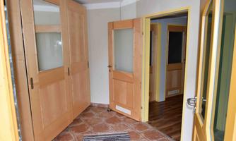 A bright hallway with wooden doors and an attractive tiled floor. There is a striped carpet on the floor.