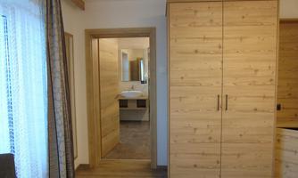 A cozy room with a wooden closet and a passage to a bathroom. The window lets in natural light and creates an inviting atmosphere.