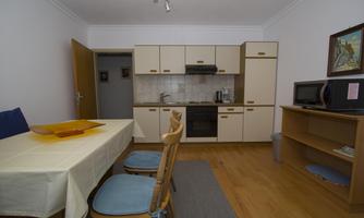 A bright kitchen with a dining table and chairs. The equipment includes a stove, refrigerator, and a microwave.