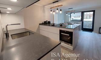 A modern kitchen with a large workspace and high-quality appliances. The room is bright and inviting, with access to an outdoor area.