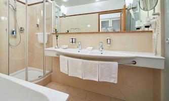 A modern bathroom with a shower and sink. The walls are painted in light colors, and fresh towels are ready.