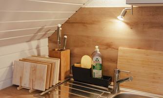 A small, modern kitchen with a wooden countertop and sinks. The walls are bright, and the lighting creates a friendly atmosphere.