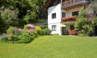 A beautiful house with a well-maintained garden full of flowers. On the terrace, there are furniture for relaxing outdoors.