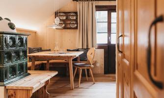 A cozy room with a wooden stump table and chairs. The walls are made of wood, and there are large windows with curtains.