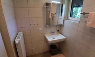 A modern bathroom with bright tiles and a sink. A window provides natural light and a pleasant atmosphere.