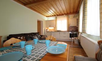 A cozy kitchen with a dining area. The table is set with blue plates and cups.