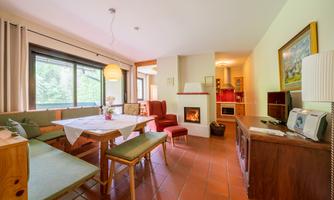 An inviting living room with a large window, a dining table, and a cozy fireplace. The decor is modern and comfortable, perfect for relaxing hours.