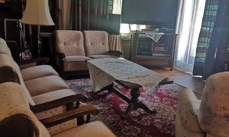 A cozy living space with a large television and comfortable sofas. A decorative rug and curtains create an inviting atmosphere.