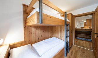 A cozy bedroom with a wooden bunk bed. The room has light walls and Provençal design.
