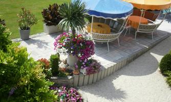 An inviting outdoor area with colorful parasols and comfortable chairs. Colorful flowerbeds create a pleasant, relaxed atmosphere.