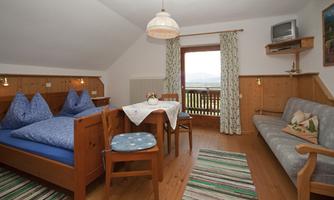 A cozy room with two single beds, a table, and chairs. Through the window, one looks out at a beautiful view.