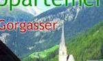 A picturesque village in the mountains with a church and majestic peaks in the background. The nature is green and inviting.
