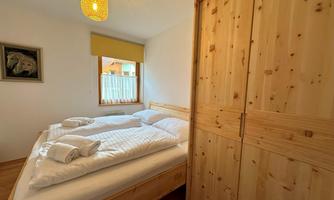 A cozy bedroom with a double bed and two pillows. The room is bright and has wooden details as well as a window with a view.