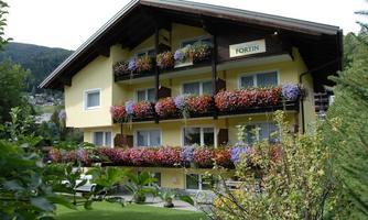 A beautiful yellow guesthouse with blooming balcony boxes. The surroundings are green and inviting.