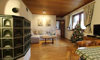 A cozy living space with a fireplace, sofa, and a dining table. In the corner stands a Christmas tree that decorates the room festively.
