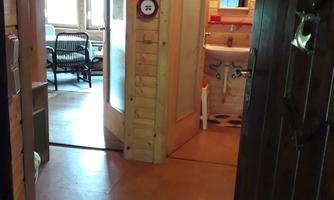 A cozy wooden room with doors and a privacy screen. One can see a simple floor and some furniture in the background.