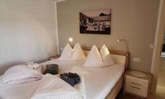A cozy bedroom with a large bed and modern furniture. The walls are painted in soft colors, and a piece of art hangs above the bed.