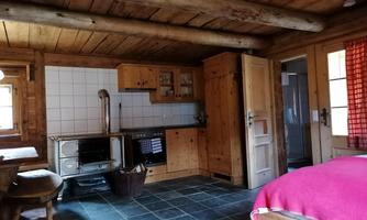 A cozy wooden apartment with a kitchen and a dining area. The decor is rustic and inviting.