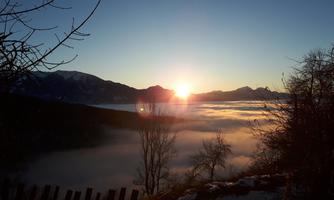 A beautiful sunrise over a misty landscape. The silhouette of the mountains is visible in the background.