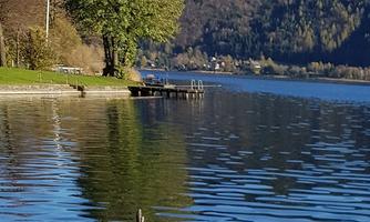 A tranquil lake surrounded by trees and mountains. The water's surface reflects the landscape.