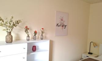 A cozy bedroom with a bright wall color and modern furniture. Decorative vases with plants and a beautiful wall picture give the room an inviting atmosphere.