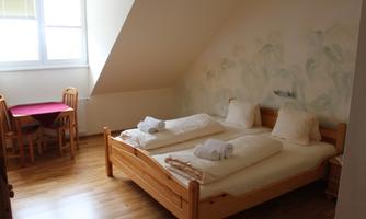A cozy bedroom with two single beds and fresh towels. A small table with chairs complements the simple, inviting atmosphere.
